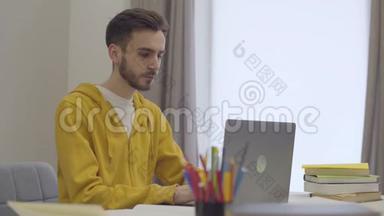 自信的白种人年轻男子与笔记本电脑工作，打哈欠和把头放在桌子上的肖像。 累坏了的学生