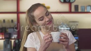 微笑的白种人女人闻咖啡的特写镜头。 年轻的女<strong>服务</strong>员在咖啡馆里<strong>享</strong>受早晨的卡布奇诺。 幸福快乐