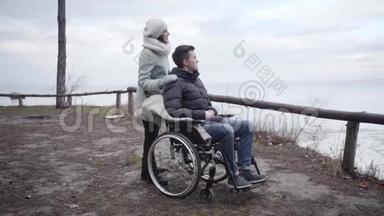 年轻积极的白人妇女触摸轮椅上残疾男子的肩膀并指向别处的肖像。 <strong>强</strong>国