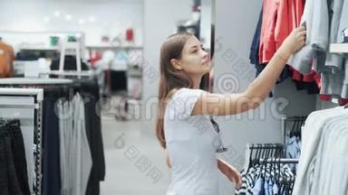 年轻女子在商场购物，为孩子挑选衣服，比较一下