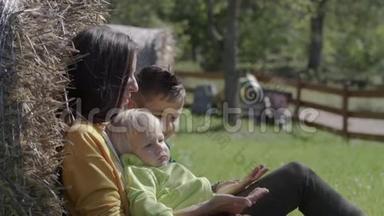 一位年轻的母亲坐在草地上和孩子们玩耍