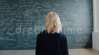 女教授在课堂上缓慢地走向黑板看公式