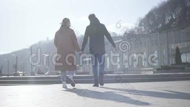 镜头跟随年轻男女在阳光明媚的秋日漫步在城市广场。 快乐的高加索夫妇相爱