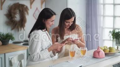 两个女人吃早餐，喝茶，看电话和微笑，网购