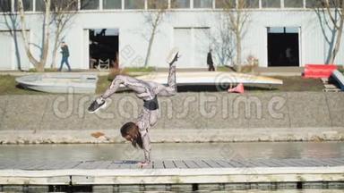年轻的女体操运动员在蓝湖附近的浮舟上表演<strong>倒立</strong>。 慢动作