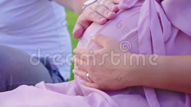 一对年轻夫妇的手放在孕妇的大肚子上。 等待孩子
