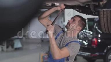 专业白种人<strong>汽车</strong>修理工拧紧<strong>汽车螺丝</strong>的肖像。 年轻的帅哥在修理店工作