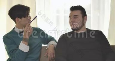 两个白人大学生坐在沙发上聊天。 男朋友在家讨论作业.. 情报