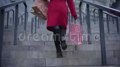 镜头跟随不可辨认的时尚女士穿着红色外套和黑色靴子在城市的楼梯上购物