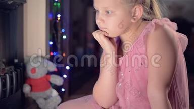 一个小<strong>悲伤</strong>失望的女孩坐在人造壁炉旁，在柔软的玩具旁边感到<strong>悲伤</strong>。 被宠坏的概念