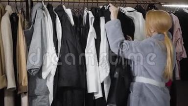 时尚的年轻白种人女人在商店里谈论着衣架上的黑色连衣裙。 时尚精品店的时尚女富豪购物