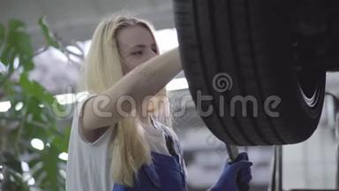 年轻美丽的白种人女人收紧车轮螺丝的肖像。 漂亮的女汽车修理工