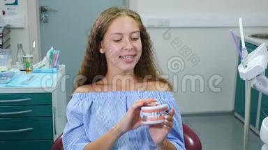 微笑的女孩带着矫形牙套在牙科椅上。 保健、牙科保健和牙科概念。 年轻快乐