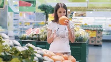 年轻的女游客在杂货店里选择南瓜，闻一闻，然后拿走它