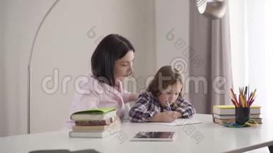 镜头接近疲惫的白种人母亲打哈欠，帮助女儿做家庭作业。 可爱的<strong>黑发女生</strong>