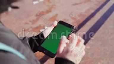 女孩手里拿着一部智能手机，手里拿着一个绿色的屏幕，在手机里沿着街道攀爬。 对Steadicam的射击