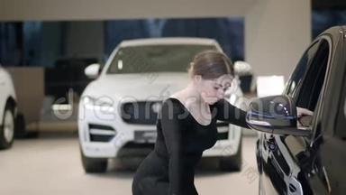 美丽的白种人妇女在汽车经销商跳芭蕾的肖像。 小型芭蕾舞演员在汽车陈列室的表演