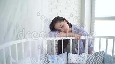 不开心的女人。 年轻的母亲，烦恼，疲惫的女人睡在婴儿床旁。