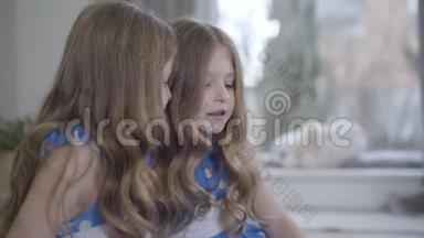 两个可爱的黑发双胞胎姐妹在家闲聊。 小白种人女孩说话，做安静的手势。 肖像