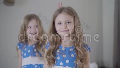 可爱微笑的白种人女孩的肖像，回首快乐的双胞胎姐妹，把手指像角一样放在兄弟姐妹`身上