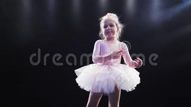 穿着粉色<strong>芭蕾舞</strong>裙的小<strong>芭蕾舞</strong>演员在舞台上跳舞。快乐的孩子。微笑。在背光里。慢<strong>动作</strong>