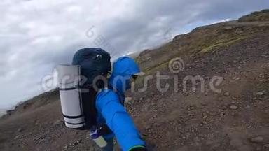 微笑青年男子徒步穿越崎岖的冰岛地形，在Fimvorduhals的大风中，每秒可达30名拳击手
