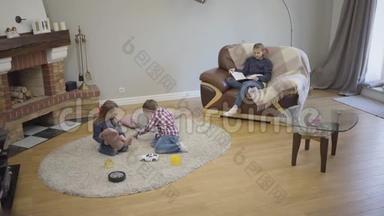 三个不同年龄的白种人儿童周末坐在家中壁炉前的长镜头。 年幼的孩子
