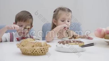 可爱的白种人男孩和女孩吃蛋糕的特写脸。 弟弟妹妹在生日那天吃甜食