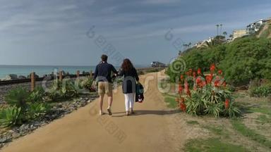 快乐的一对夫妇在海滩上<strong>牵手散步</strong>，享受美好的一天。 列车通过太平洋冲浪旅行假期