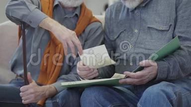 两个面目全非的白人男人看着老照片。 男人白发苍苍的退休者在室内回忆往事。 怀旧