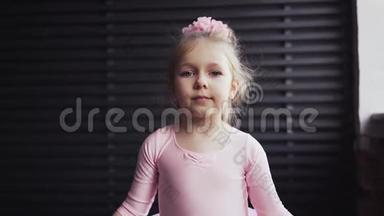 穿着<strong>粉色</strong>芭蕾舞裙的儿童芭蕾舞演员看起来是金发。 站在窗边<strong>微</strong>笑.. 慢动作
