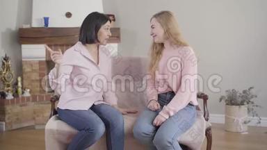 年轻的黑发白种人女人在室内和金发女孩有感情地交谈。 妈妈和女儿在家休息。 <strong>信托基金</strong>