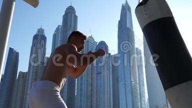 以迪拜城市景观为背景的肌肉男击打沙袋