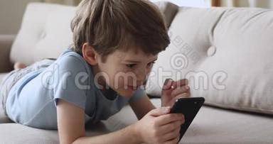 快乐的小童男孩在玩手机网络游戏。