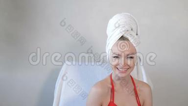 美丽的年轻微笑女人的肖像，头上戴毛巾在豪华健康中心。 对着镜头微笑着复制