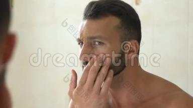 不快乐的男人在浴室镜子前<strong>检查</strong>脸上的<strong>皱纹</strong>，衰老