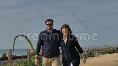 快乐的一对夫妇在海滩上<strong>牵手散步</strong>，享受美好的一天。 靠近太平洋冲浪缆车旅行假期