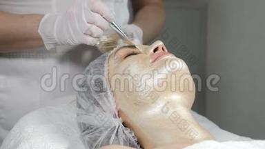 美容师在美女脸上敷美容面膜。化妆金面罩提升效果