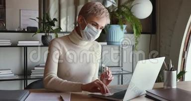 女商人戴着医用口罩清洁手提电脑键盘和消毒液