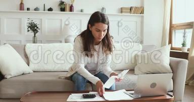 一个<strong>认真</strong>的年轻女人在家看文书工作计算账单