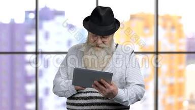 老爷爷在平板电脑上滚动他的社交媒体。