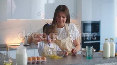 妈妈教女儿用搅拌器打面团做馅饼。 爱的母女一起做馅饼。 妈妈