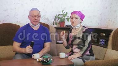 犹太已婚夫妇戴着防护面具，在家中的沙发上<strong>喝酒</strong>，以防止冠状病毒