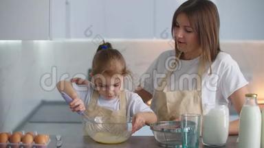 一个学龄前女孩帮妈妈做饭。 爱的母亲教女儿按家庭做饭