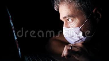 忧心忡忡的男人戴着面罩，透过笔记本电脑上的一个新闻网站看。 最新冠状病毒爆发资讯
