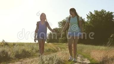 夏天公园里快乐的徒步旅行者女孩。 自由的女人手拉手，女孩在乡下的路上旅行。 女旅客