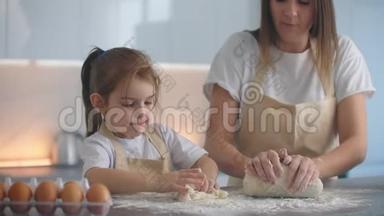 妈妈和女儿一起用手做面团做一个晚上的蛋糕。 一起做的透明晚餐