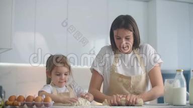 母亲和女儿在厨房用面团模具做饭。 母女俩抱着心形面团模具.. 把它刻下来