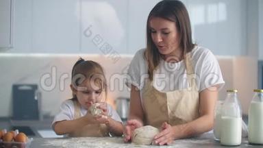 母亲和女儿在厨房用面团模具做饭。 母女俩抱着心形面团模具.. 把它刻下来