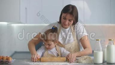 妈妈帮女儿在厨房里卷面团来烤饼干。 妈妈和女儿一起在厨房里烤披萨。 女孩